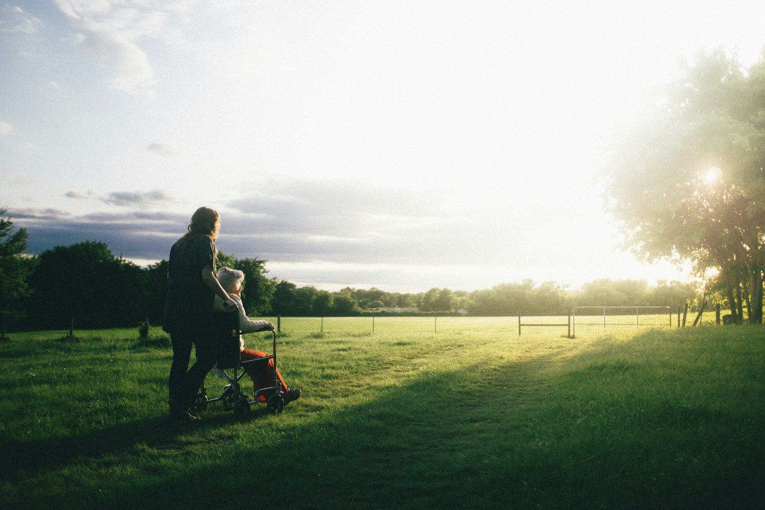 Cuidadora e idosa observando o fim de tarde em um campo aberto
